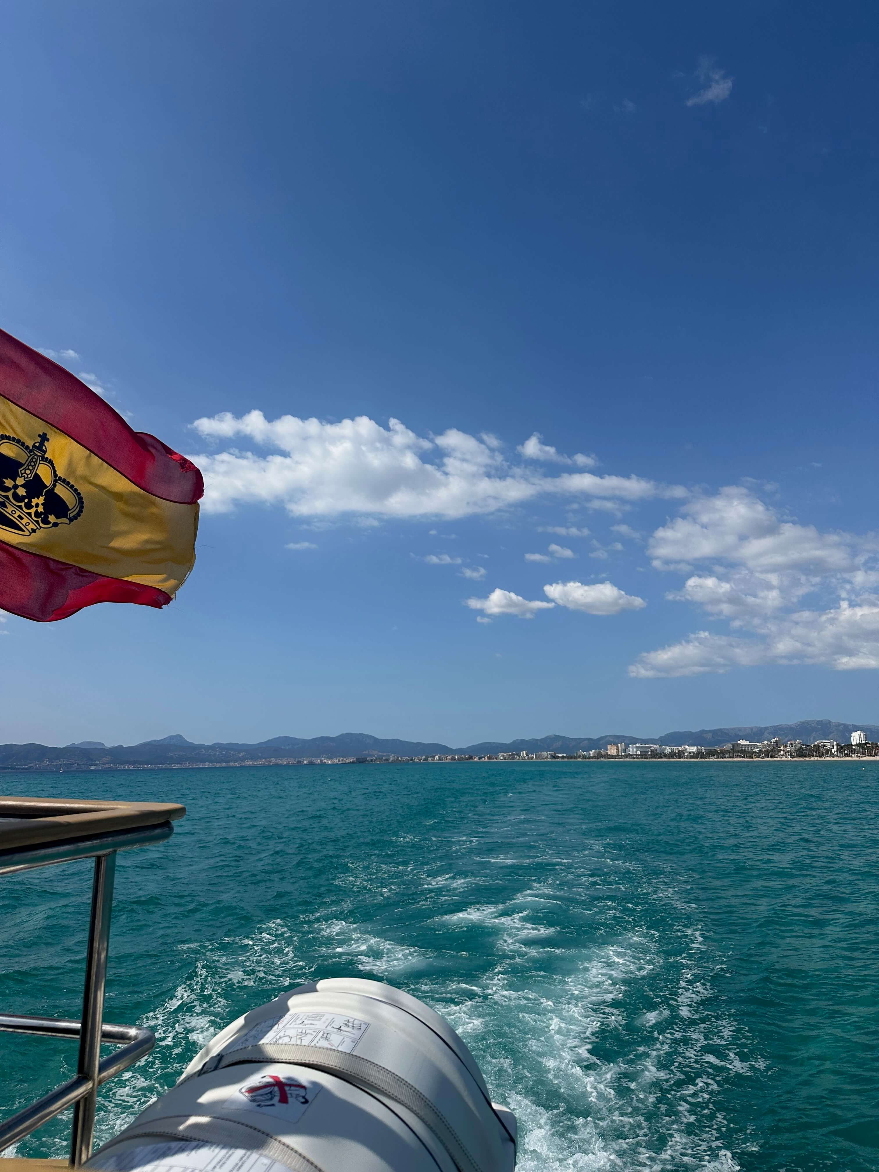 Wake trailing behind a boat off the coast of Spain with a Spanish flag flying